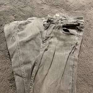 Grå jeansbyxor från Gina Tricot - Säljer ett par grå jeansbyxor från Gina Tricot i storlek 164. Klassisk femficksmodell med dragkedja och knapp framtill. Byxorna har en rak passform och är tillverkade i ett mjukt bomullsmaterial med lite stretch. Perfekta till en avslappnad look. Storlek 164