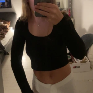 Svart croppad långärmad topp - Säljer en svart croppad topp med lång ärm och djup rundad urringning. Toppen är tight i passformen och har en stilren, enkel look som är lätt att matcha. Köpt på Shein eller New Yorker om jag inte minns fel