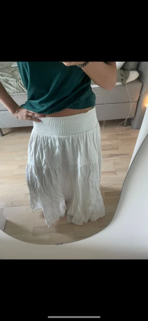 Vit långkjol från Bik Bok - Säljer en vit långkjol från Bik Bok i storlek M. Kjolen har bred smock i midjan och är gjord i ett mjukt, lätt material med volangdetaljer. Perfekt för dig som gillar flowy och avslappnad stil. Fråga gärna om fler bilder eller info!