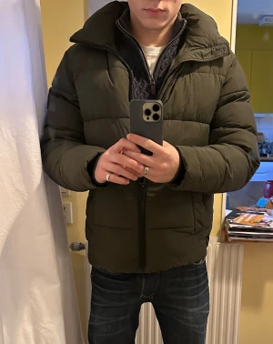 Mörkgrön pufferjacka från Calvin Klein - Säljer min mörkgröna pufferjacka från Calvin Klein med huva och dragkedja i storlek M. Säljer den då jag tyvärr inte längre har användning av denna. Jackan har en quiltad look och patch med logga på ärmen. Perfekt för kalla dagar och har en clean, modern vibe. Jackan har en normal passform. Om du har frågor hör gärna av dig. Priset kan diskuteras. 