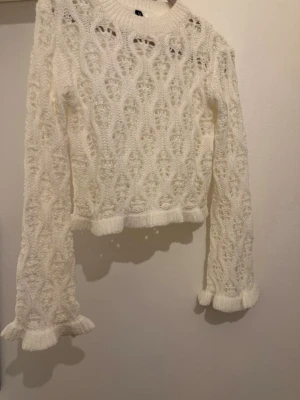 Vit stickad croppad tröja med volang - Använt ca 2 gånger. I fint skicks köptes från HM. Säljs pågrund av flyttstädning. 