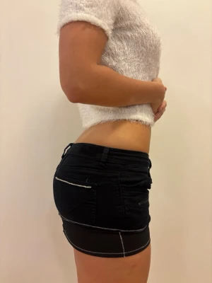 Svart kortkjol med dragkedjor - Säljer en svart kortkjol med coola dragkedjor och kontrastsömmar. Kjolen har fickor både fram och bak samt bälteshällor. Materialet känns som bomull med lite stretch och har en tight passform. Perfekt för dig som gillar edgy och trendig stil.😍😍