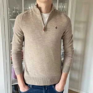 Beige Merino John Zip tröja från Morris - S - Jag säljer den här riktigt populära Merino John Zip tröjan från Morris. Den är i storlek S men upplevs mindre så utgå ifrån måtten (kanske krymt lite i tvätten).Tröjan är nästan som ny och har inte använts mycket alls. Den kostar 1799kr ny och jag säljer den här för 599kr. Tveka inte att höra av er!                                                              Mått: Längd=61cm. Från botten till toppen.        Bredd=42cm. Bredden under armhålorna.