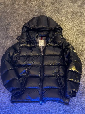 Svart Moncler Maya - Svart Moncler Maya, helt nyskick, använt någon enstaka gång. QZ skannar. Storlek 3-motsvarar S och M. Förpackning medföljer. Hör gärna av er vid frågor och funderingar!