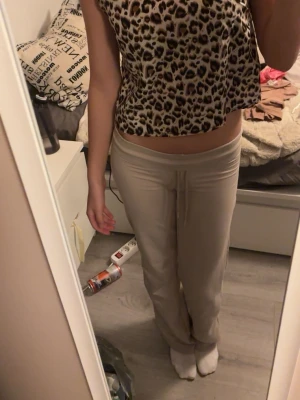 Leopardmönstrad croppad linnetopp - Säljer en croppad linnetopp med leopardmönster i beige, svart och brunt. Toppen är ärmlös och har en rak, loose passform som sitter snyggt på kroppen. Perfekt för dig som vill sticka ut med ett djuriskt print.