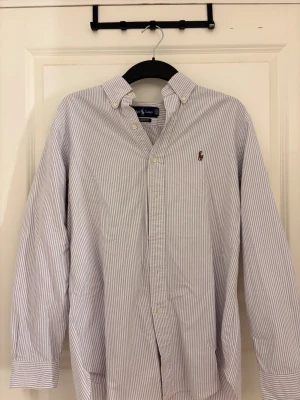 skjorta från Ralph Lauren - Snygg klassisk skjorta från Ralph Lauren i vit och ljusblå randigt mönster. Classic fit och stilren. Använd sparsamt och i mycket bra skick. Passar både till vardags och mer uppklätt 👔       ordinarie pris: ca 1300kr 