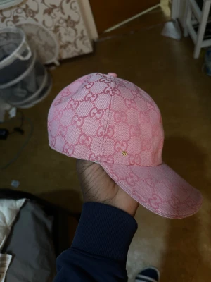 Rosa keps - Säljer en snygg rosa keps  i storlek M, med det klassiska mönstret över hela kepsen. Kepsen är tillverkad i bomull och har en böjd skärm. Perfekt för dig som vill sticka ut med en lyxig accessoar.