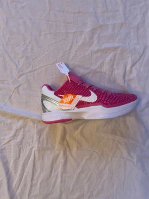 Nike Kay Yow ”think pink” Kobe 6 Protro sneakers - Unika Nike Kobe 6 Protro Kay Yow ”think pink” sneakers i rosa och vitt med coolt reptilmönster på ovandelen. Skon har snörning, låg profil och detaljer i silver. Insidan har Kay Yow-logga och yttersulan har Kobes ikoniska logotyp. Kobes är små i storlek så de passar för er som har 43 och kanske 44. Boxen ingår självklart, glömde bara ta bild på den, kan ändra om ni vill. 