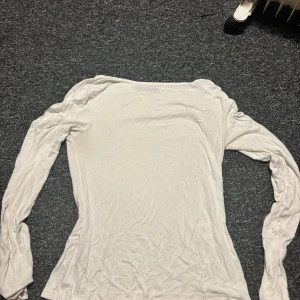 Vit långärmad topp från 157 - Säljer en enkel och stilren vit långärmad topp från 157 i storlek M. Toppen har en rundad hals och är figurnära i modellen. Materialet känns mjukt och lätt, perfekt att matcha med jeans eller kjol. Passar dig som gillar minimalistisk stil.