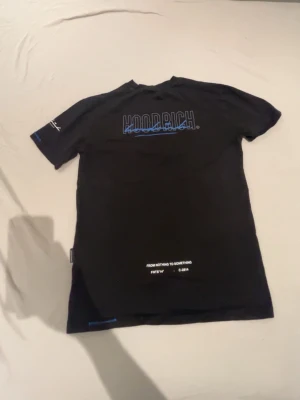 Svart Hoodrich T-Shirt - Svart Hoodrich t shirt i storlek XS med mönster både framsida och baksida.