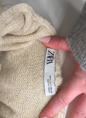 Beige stickad polotröja från Zara - Krämvit stickad tröja från ZARA i storlek S. Modellen har hög, mjuk polokrage och en avslappnad passform med något vidare ärmar. Tjockare, varm stickning som passar perfekt för höst och vinter. Klassisk och lättmatchad färg. I gott skick.