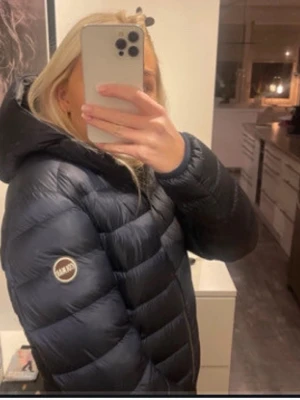 Mörkblå Colmar pufferjacka  - Säljer min  mörkblå pufferjacka från Colmar Originals med huva. Materialet är polyester och jackan är perfekt för kyliga dagar. Defekter på underarmen som är täckta, men syns inte vid användning! Det är storlek 40 men passar som en S/ M 