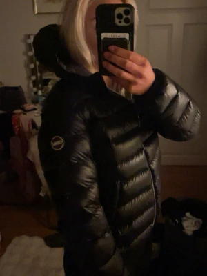 Svart Colmar pufferjacka med huva - Säljer min colmar jacka då den inte kom till användning. Så den är iprincip oanvänd. Jackan har och dragkedja framtill, ett stilrent, quiltat mönster och logotyp på ärmen och två fickor med dragkedja. Mycket bra material som inte släpper in kyla och bibehåller värme!