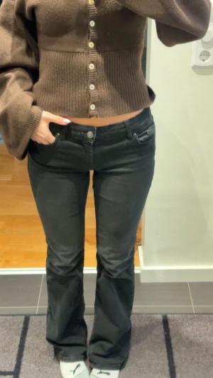 Svarta bootcut jeans - Snygga svarta jeans med bootcut-snitt och klassisk femficksdesign. Jeansen har låg midja och är tillverkade i ett mjukt och stretchigt denim-material som sitter bekvämt. Passformen är normal och benen är lätt utsvängda nedtill för en trendig look.