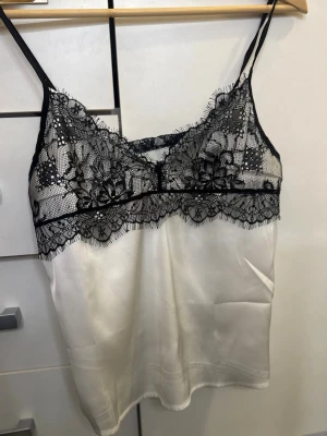 Vit linnetopp med svart spets - Säljer denna spetstopp som jag aldrig använt då den var för liten på mig. Ingen etikett där det står vart den är ifrån eller vilken storlek det är. Men skulle säga det är Xs-S🩷