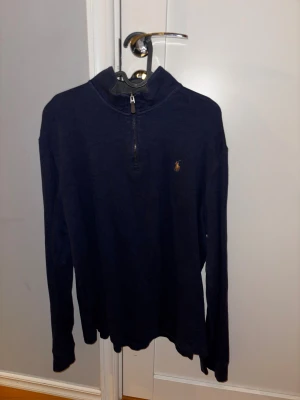 Marinblå half zip tröja från Polo Ralph Lauren - Snygg marinblå långärmad tröja från Polo Ralph Lauren med half zip och klassisk broderad logga på bröstet. Tröjan har en hög krage och är gjord i mjuk bomull, perfekt för chill dagar eller när du vill se lite extra fräsch ut. Skriv för fler bilder eller vid intresse!😊