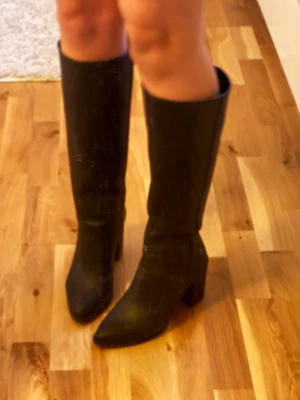 Svarta höga stövlar med klack - Säljer mina jätte fina svarta stövlar med grov struktur i skinnimitation, eftersom dem tyvärr är försmå. Modellen har spetsig tå och stabil hög klack. Stövlarna är under knee. Perfekt för en uppklädd look😊💕 NYPRIS : ca 700kr.          (Använd fåtal gånger pga fel storlek så dem är inte ingångna) klacken är ca 7 cm