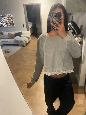 Grå croppad tröja med spetskant ONLY - Grå croppad tröja från ONLY med rund halsringning och lång ärm med spets vid kanten