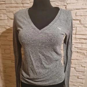 V-ringad tröja Hollister - Snygg grå långärmad tröja från Hollister med v-ringad hals. 