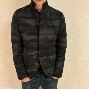 Camouflage jacka från Zadig & Voltaire - Snygg camouflage jacka från Zadig & Voltaire. Jackan har en quiltad design med långa ärmar och en stilren look. Perfekt för att hålla värmen med stil. Den har en diskret dragkedja och knappar framtill. Helt ny med tags. Jackan är storlek XS men passar S