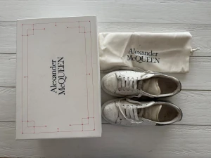 Alexander McQueen vita sneakers - Säljer ett par chunky vita sneakers från Alexander McQueen med metallic-silver detaljer på hälen och logga. Skorna har rund tå, platt sula och klassisk snörning. Tillverkade i skinn och kommer med originalkartong och dustbag.