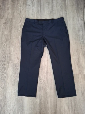 Dressma Kostymbyxor – XL – Marinblå -  Märke: Dressman – Well Dressed  Storlek: XL Färg: Marinblå – lätt att matcha med skjorta eller kavaj  Material: Polyester – slitstarkt och lättskött  Skick: Mycket bra, knappt använda 
