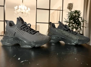 Oanvända Sneakers från Steve Madden  - Säljer ett par grå chunky sneakers från Steve Madden med ovandel i textil och dekorativa glittriga strasstenar. Skorna har tjock sula och snörning framtill. Märkeslogga på sidan och coolt, futuristiskt utseende som sticker ut. 