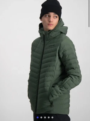 Grön skidjacka från Peak Performance - Snygg mörkgrön pufferjacka/skidjacka från Peak Performance med huva och svarta dragkedjor. Jackan har quiltad design, två sidofickor med dragkedja och justerbara ärmslut. Perfekt för kalla dagar och har en clean, sportig look. Även perfekt för skidåkning. Mycket bra i skick och använd en säsong i backen. Nypris 2799kr säljer för 1800kr. ( kan diskutera pris vid snabb affär)