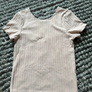 Ljusrosa ribbad topp från BikBok - Säljer en ljusrosa ribbad topp från BikBok i storlek L. Toppen har korta ärmar, rund halsringning och ett diskret randigt mönster. Perfekt att matcha med jeans eller kjol för en enkel och snygg look.