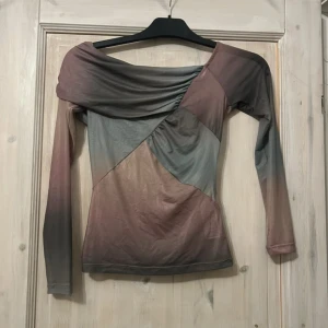Offshoulder topp i dova färger - Säljer en långärmad offshoulder topp med asymmetrisk design i dova nyanser av grått, brunt och lila. Toppen har en cool patchwork-känsla och är figurnära med mjukt, stretchigt material. Perfekt för dig som gillar unika plagg med edge.