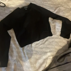 Svart croppad tröja från New Apparel - Svart, stilren croppad tröja från New Apparel i storlek M. Tröjan har lång ärm