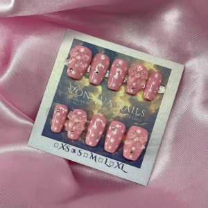 PinkBling (S);Short Coffin - Handgjorda press-on naglar i en söt rosa färg med ljusrosa prickar, kristall stenar och 3D-rosetter i transparent akryl. Naglarna har en kort ballerina form och kommer i S: 15 mm, 11,5 mm, 12 mm, 11 mm, 9 mm . Perfekt för dig som vill ha en girly och unik look.
