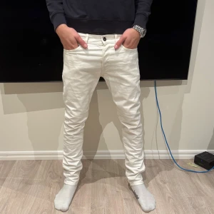 Denim jeans - Säljer ett par vita jeans med slim passform och klassisk femficksdesign. Byxorna har en smal siluett, knappstängning och är tillverkade i mjukt bomullstyg. Perfekt för dig som gillar stilrena och moderna jeans. Storleken i byxorna är W32 & L32.