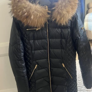 Svart dunjacka Rockandblue med päls - Svart dunjacka från Rockandblue med stor fluffig päls , guldfärgade dragkedjor och leopardmönstrat foder. Jackan har inga märken och är som ny. Den är i storlek 42 men sitter som en S/M.  Nypris är  5000 kr 