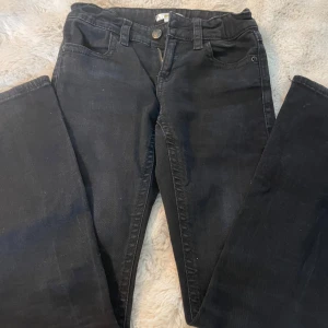 Svarta jeans från Gina Tricot - Svarta jeansbyxor från Gina Tricot med klassisk femficksdesign och snygga detaljer på bakfickorna. Byxorna har bälteshällor, knapp och dragkedja framtill. Passar dig som gillar en enkel och stilren look. De är bootcut 