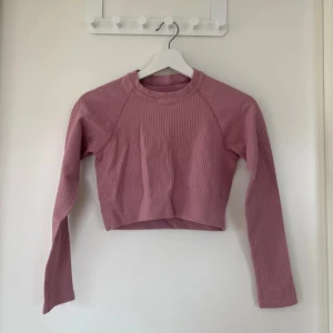 Rosa ribbad croppad långärmad topp - Säljer en ljusrosa croppad topp med ribbad struktur och långa ärmar. Toppen är tillverkad i mjuk och stretchig polyester med 4% elastan, vilket gör den riktigt skön att bära 