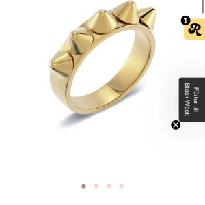 Guldfärgad ring med nitar - Cool guldfärgad ring med fem konformade nitar runt ovansidan. Ringen har en chunky design och ger en edgy vibe till din stil. Perfekt för dig som gillar att sticka ut och vill ha något unikt på fingret. Storlek 16.00mm-xs