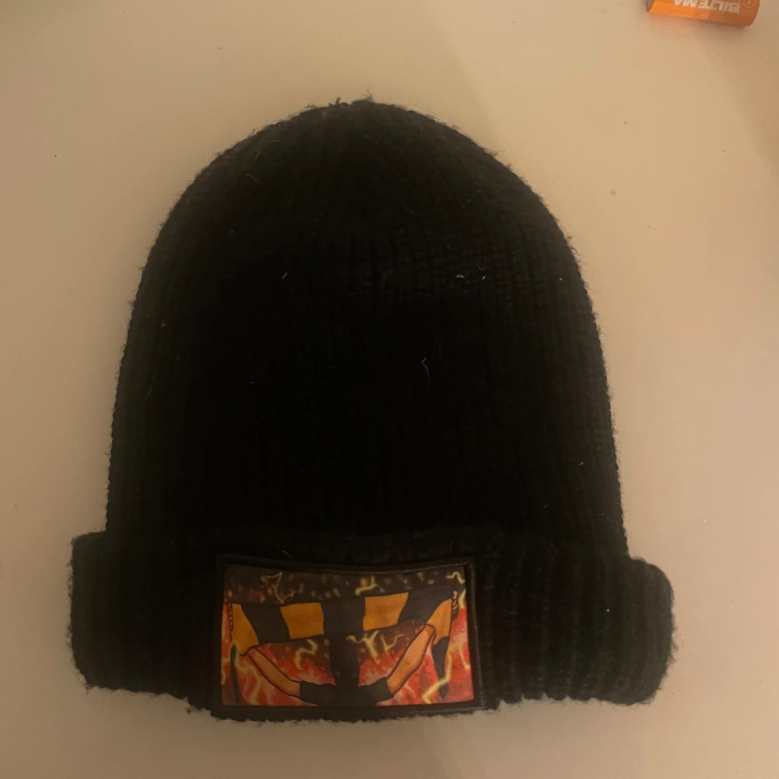 Svart stickad mössa med eldpatch