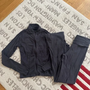 Mörkgrå zip-tröja från Gina Tricot - Superskön mörkgrå långärmad zip-tröja från Gina Tricot, perfekt för träning eller chill. Tröjan har dragkedja hela vägen och en hög krage. Materialet är mjukt och stretchigt, vilket gör den riktigt bekväm att bära. Snygg och enkel design som funkar till allt.