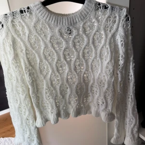 Vit stickad tröja med vågigt mönster - Superfin vit stickad tröja med vågigt och håligt mönster. Tröjan har långa ärmar och ribbade muddar vid hals, ärmslut och nederkant. Perfekt för lager-på-lager och ger en riktigt mysig vibe.