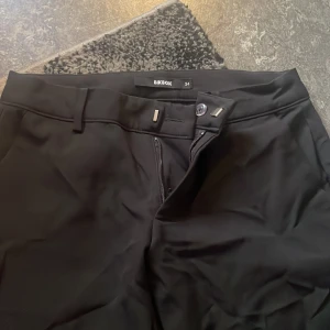 Svarta kostymbyxor från Bik Bok - Snygga svarta kostymbyxor från Bik Bok i storlek 34. Byxorna är bootcu, knapp och dragkedja framtill samt diskreta fickor bak. Perfekta för en clean och stilren look.
