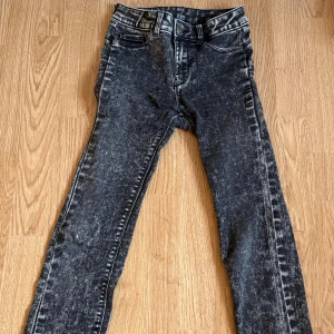 Svarta skinny jeans med tvättad look - Snygga svarta jeans med tvättad, lite sliten look och skinny passform. Klassisk femficksmodell med bälteshällor och dragkedja. Perfekt för dig som gillar en cool och avslappnad stil.