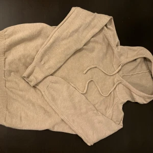 Beige Kashmir hoodie med snörning - En stilren beige kashmir hoodie med huva och snörning. Tröjan har långa ärmar och ribbade muddar vid ärmslut och nederkant. Perfekt för chill dagar och enkel att matcha.