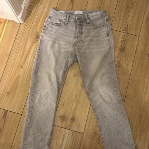 Grå loose jeans från Jack & Jones - Snygga grå jeans från Jack & Jones i modellen Loose/Chris. De har en loose passform och klassisk femficksdesign med dragkedja och knapp. Jeansen är tillverkade i mjukt denim och har en cool, ljusgrå tvätt som ger en avslappnad vibe.