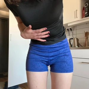 Blå träningsshorts från Gavelo - Säljer ett par blå tighta träningstights-shorts från Gavelo med diskret geometriskt mönster. De har en kort passform som sitter tajt mot kroppen. Perfekta för gymmet eller löpning. Materialet är stretchigt och andas bra.