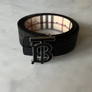 Vändbart burberry bälte - Fett vändbart bälte från Burberry med svart-silvrigt spänne i storlek 95/110cm, hålgörare ingår. Nytt skick och fraktas inom 24h✅