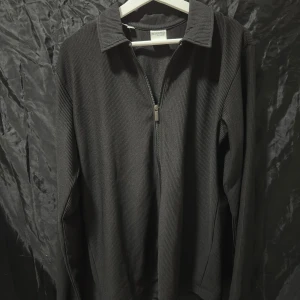 Svart tröja från Selected Homme - Svart långärmad tröja från Selected Homme med ribbad struktur och krage. Tröjan har två dragkedjor framtill och är tillverkad i ett mjukt material. Perfekt för dig som gillar stilrena och enkla plagg. Säljer den för att den är lite stor och inte kommer till användning. Storlek S (passar M) skick 9,5/10