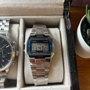 Casio digital klocka i silver - Klassisk digital klocka från Casio med rektangulär display och länkarmband i silverfärgad metall. Klockan har funktioner som alarm, kronograf, datumvisning och bakgrundsbelysning. Perfekt retrostil med tydlig digital skärm och vattenresistens.