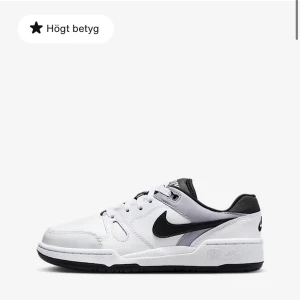 Vita Nike sneakers med svart swoosh - Snygga vita Nike sneakers med svart swoosh på sidan och svart insida. Skorna har klassisk snörning och är tillverkade i skinnliknande material. Perfekta för dig som gillar en clean och sportig look. Och inte använd så mycket.
