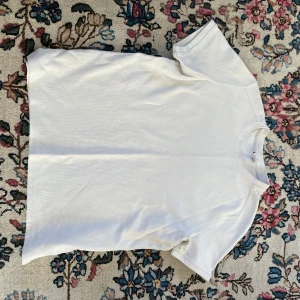 Vit t-shirt från Bershka - Vit t-shirt från Bershka i storlek L. Klassisk rund hals och korta ärmar, tillverkad i mjuk bomull. Enkel och clean design utan mönster eller tryck, perfekt för en chill och stilren look.